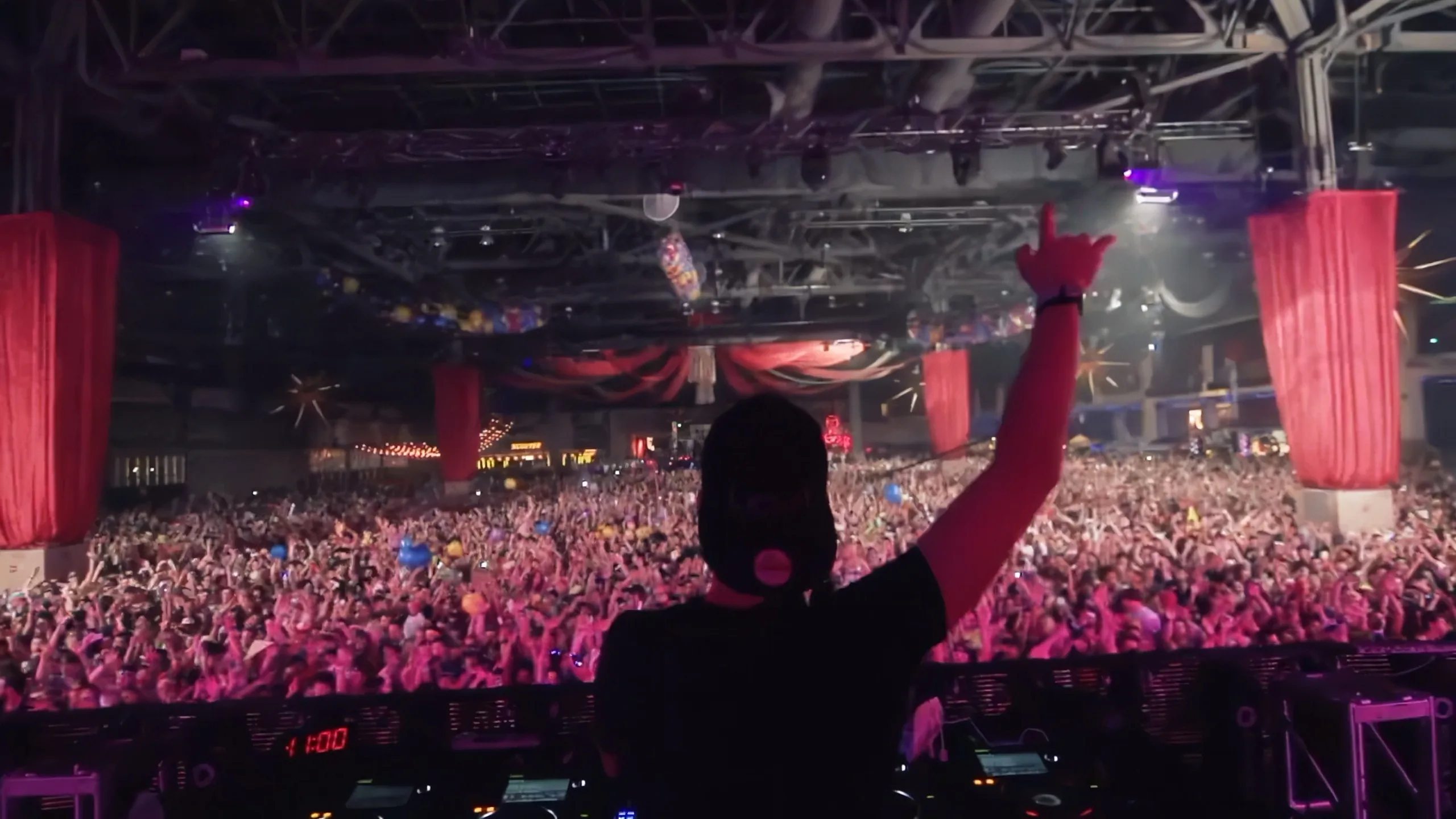 EDM festival crowd with DJ performing under stage lighting